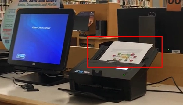 A computer and a scanner placed alongside with some papers in scanner tray