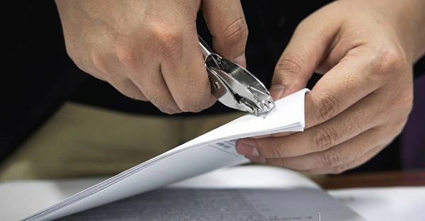a person unstapling some documents in his hand